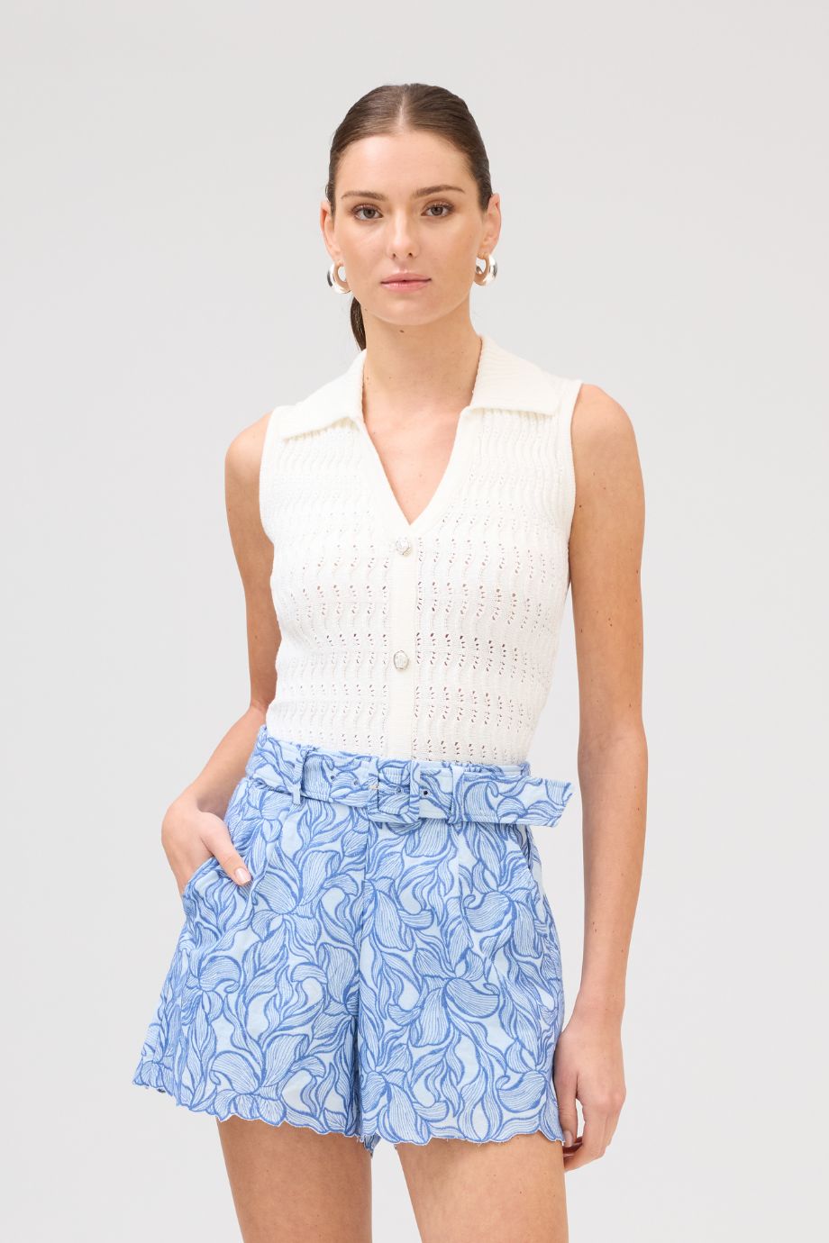 woman wearing blue embroidered scalloped hem Ainsley shorts with belt paired with white knit Bodhi top