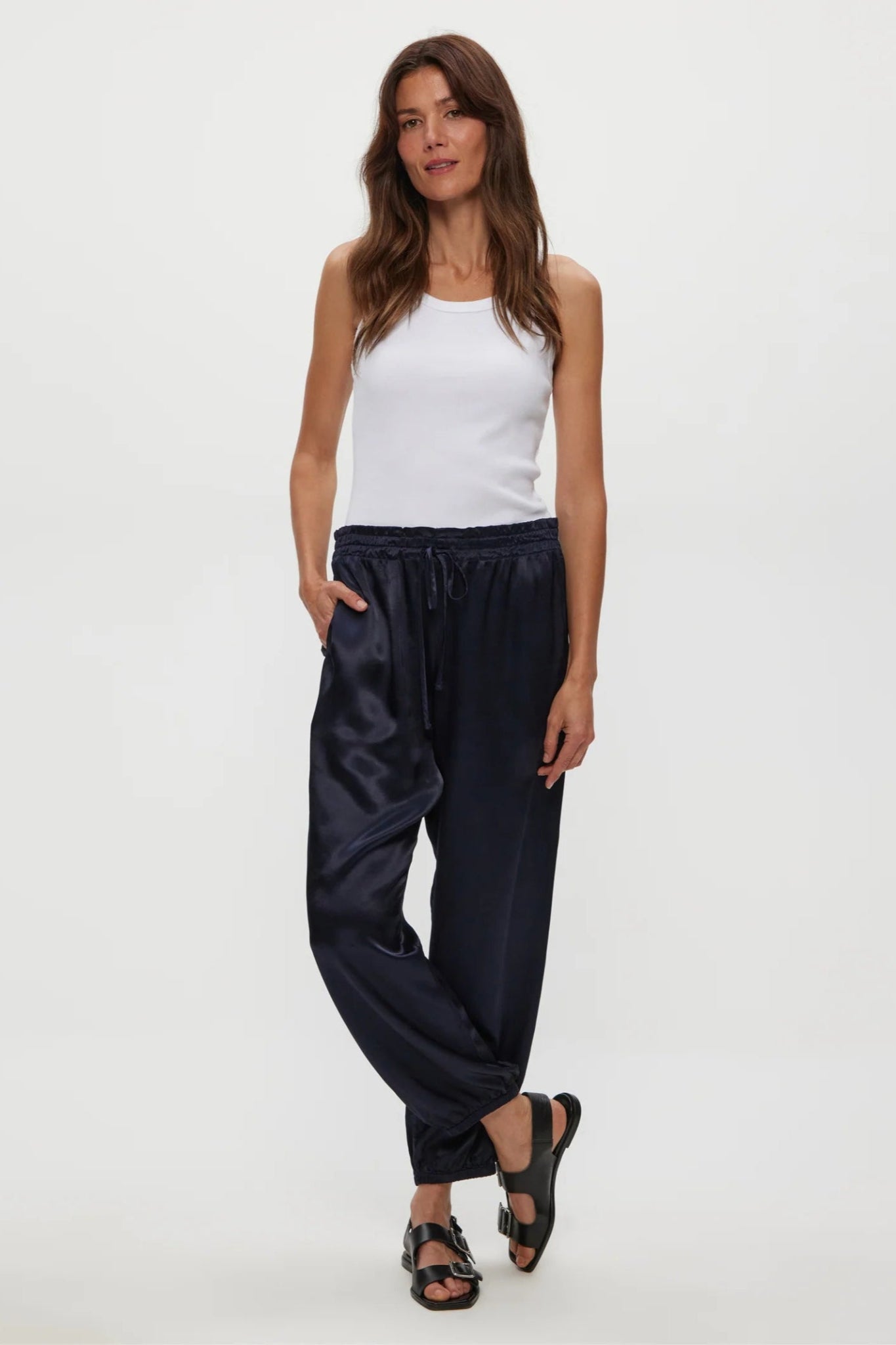 Woman wearing navy pants and a white top on a white background